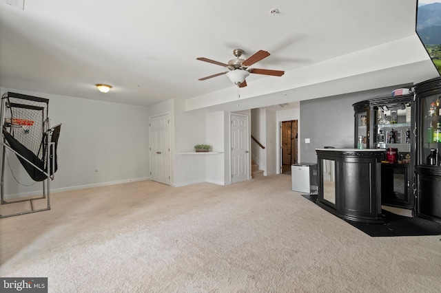 living area featuring stairway, a ceiling fan, baseboards, carpet floors, and a bar