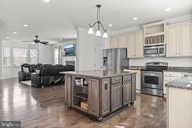 kitchen with cream cabinetry, appliances with stainless steel finishes, dark wood-style flooring, and ornamental molding