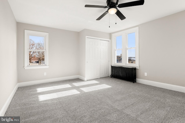 unfurnished bedroom with radiator, light carpet, ceiling fan, and a closet