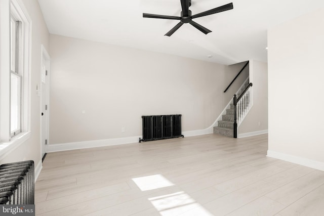 unfurnished living room featuring ceiling fan, radiator heating unit, and light hardwood / wood-style floors