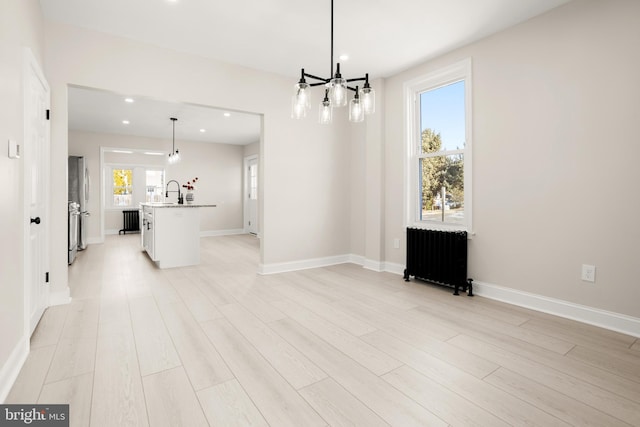 interior space featuring sink, radiator heating unit, and light hardwood / wood-style flooring