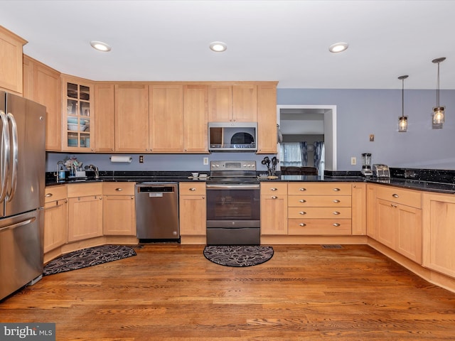 kitchen featuring light brown cabinetry, decorative light fixtures, light wood-type flooring, and appliances with stainless steel finishes