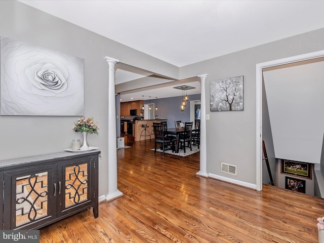 hallway with ornate columns and hardwood / wood-style floors