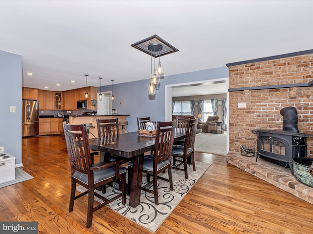 dining area with a wood stove and light hardwood / wood-style floors