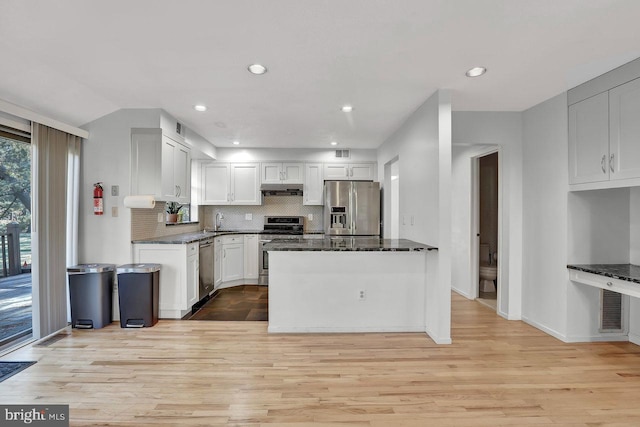 kitchen with tasteful backsplash, appliances with stainless steel finishes, white cabinets, and dark stone counters