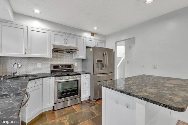 kitchen with white cabinetry, stainless steel appliances, sink, and dark stone counters