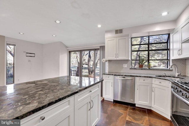 kitchen featuring white cabinetry, appliances with stainless steel finishes, and dark stone counters