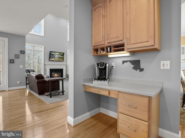 kitchen featuring light countertops, light wood-style floors, open floor plan, light brown cabinets, and built in study area