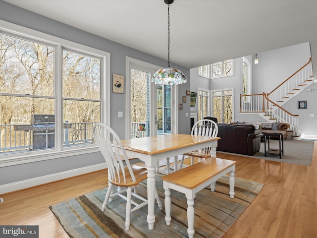 dining space with stairs, light wood-type flooring, and baseboards