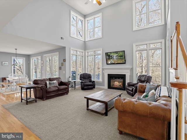 living area with wood finished floors, a wealth of natural light, a glass covered fireplace, and visible vents