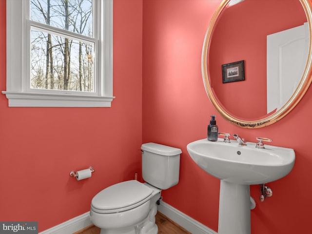 bathroom featuring toilet, baseboards, and a sink