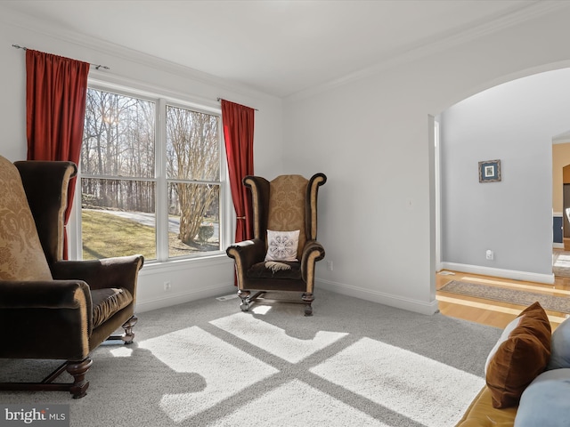 sitting room with light carpet, baseboards, arched walkways, and ornamental molding