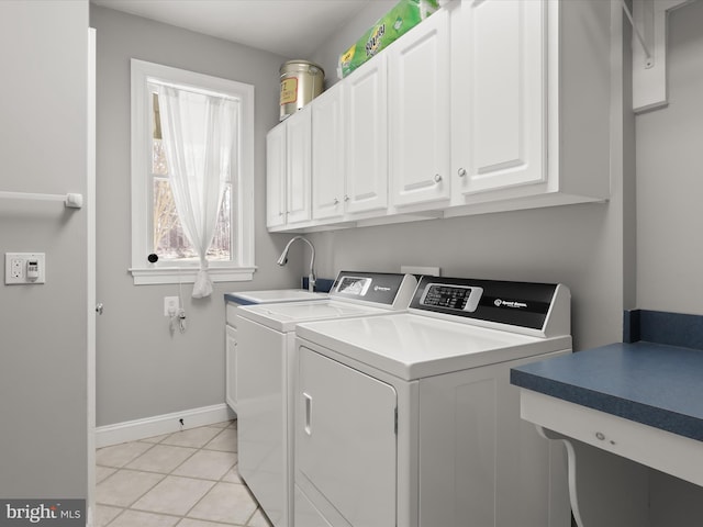 clothes washing area featuring cabinet space, baseboards, separate washer and dryer, a sink, and light tile patterned flooring