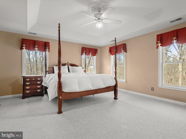 carpeted bedroom featuring a raised ceiling, visible vents, and baseboards