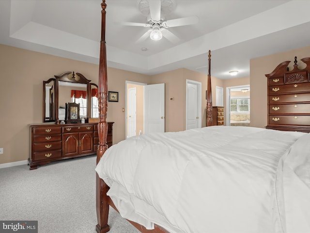 bedroom featuring baseboards, a raised ceiling, a ceiling fan, and light colored carpet