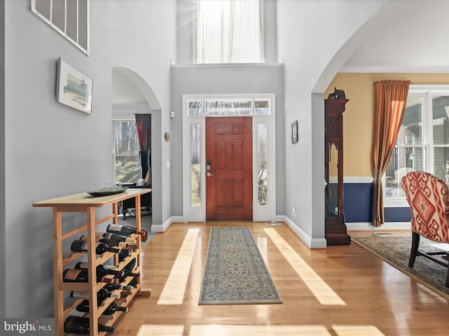 entryway with a wealth of natural light, visible vents, arched walkways, and wood finished floors