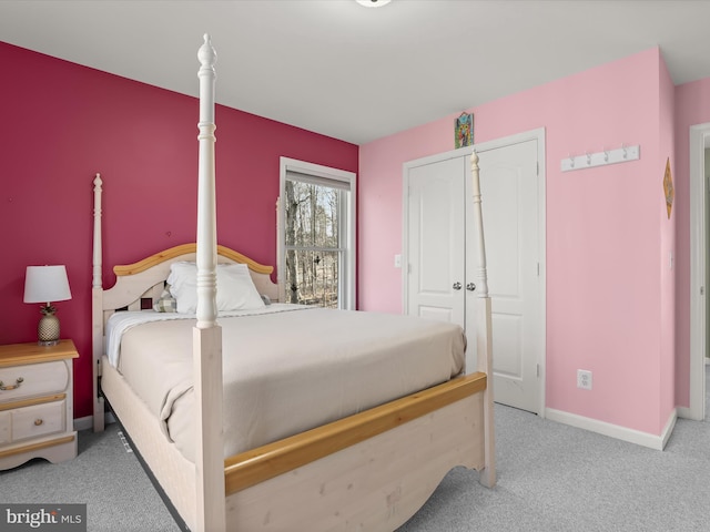 bedroom featuring baseboards, a closet, and light colored carpet