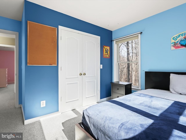 carpeted bedroom featuring a closet and baseboards