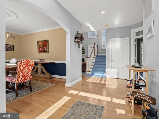 entrance foyer with arched walkways, wood finished floors, visible vents, baseboards, and stairs