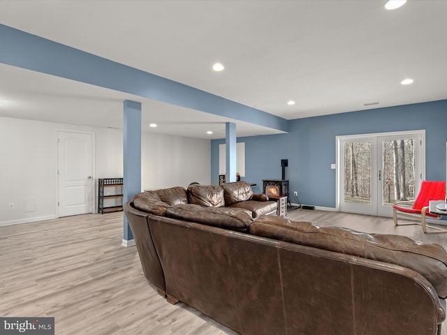 living room with recessed lighting, visible vents, baseboards, light wood finished floors, and a wood stove