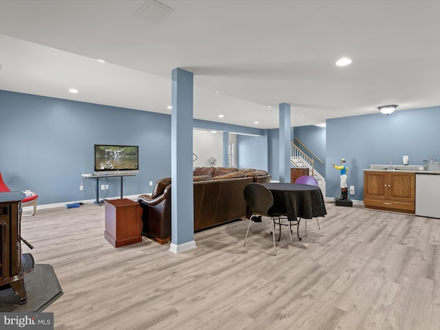 living room with light wood finished floors, baseboards, wet bar, and stairway