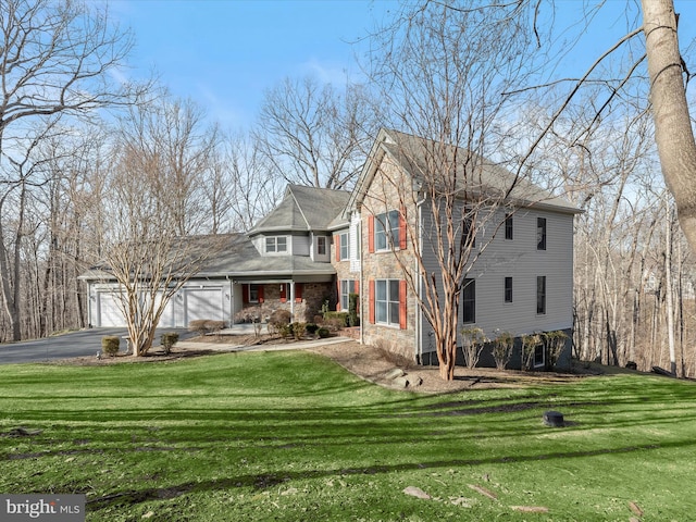 view of front of property with covered porch, aphalt driveway, a front yard, and an attached garage