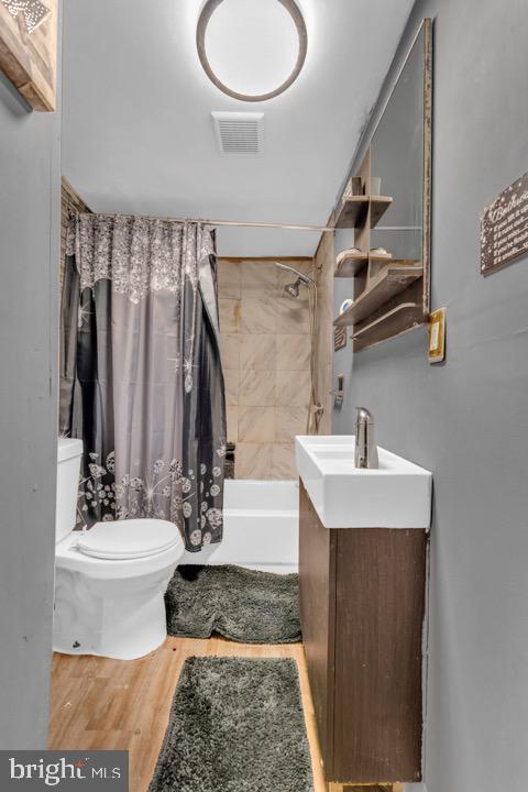 full bathroom featuring vanity, toilet, hardwood / wood-style floors, and shower / bath combo with shower curtain