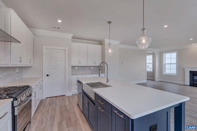 kitchen featuring blue cabinetry, sink, white cabinetry, hanging light fixtures, and appliances with stainless steel finishes