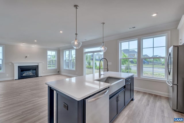 kitchen featuring sink, crown molding, decorative light fixtures, a center island with sink, and appliances with stainless steel finishes