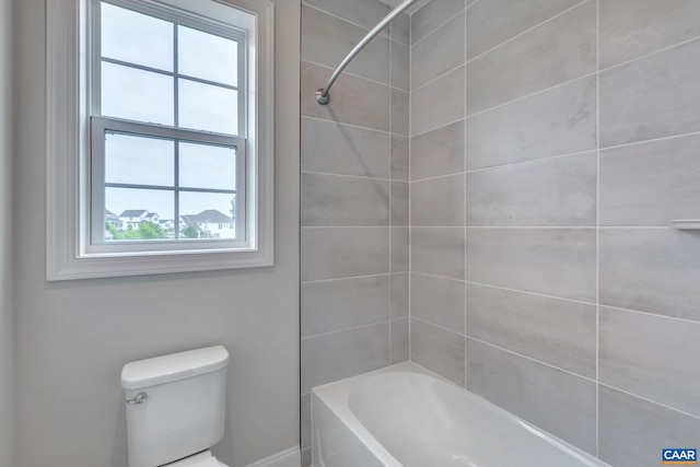 bathroom featuring tiled shower / bath combo and toilet