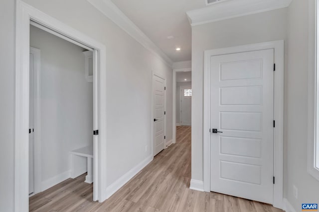 hall with ornamental molding and light hardwood / wood-style floors