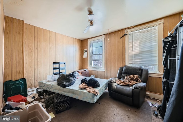 bedroom with multiple windows, ceiling fan, and wood walls