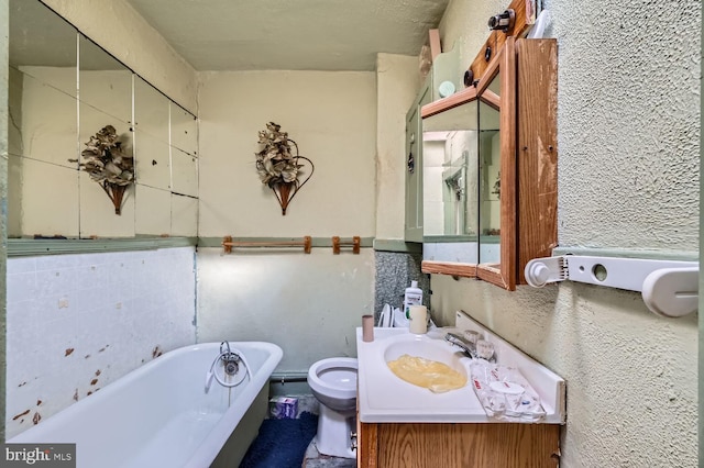 bathroom featuring vanity, toilet, and a washtub