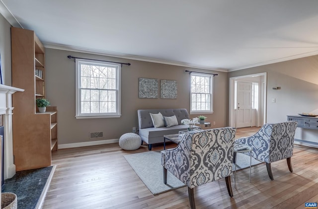 living room with ornamental molding, a high end fireplace, and light hardwood / wood-style flooring