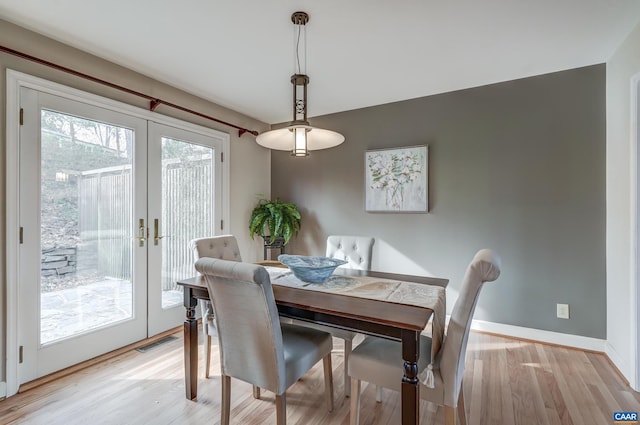 dining space with light wood-type flooring and french doors