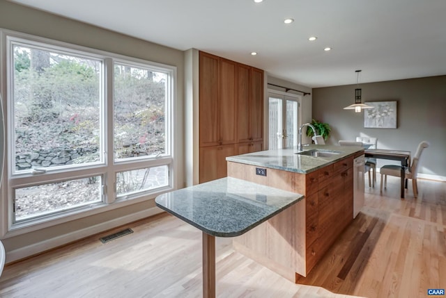 kitchen with french doors, sink, decorative light fixtures, dishwasher, and a kitchen island with sink