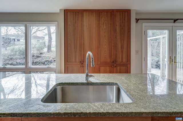 kitchen featuring sink, light stone counters, and french doors