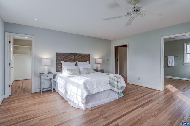 bedroom featuring a closet, a spacious closet, ceiling fan, and light hardwood / wood-style flooring