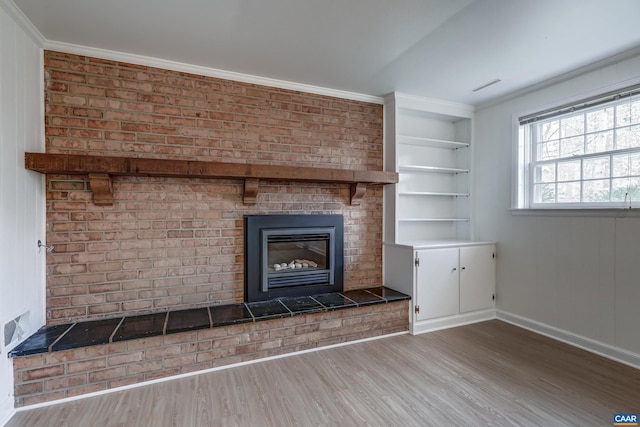 unfurnished living room with a brick fireplace, hardwood / wood-style flooring, built in features, and ornamental molding