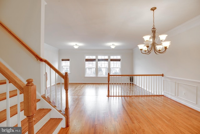 unfurnished room featuring an inviting chandelier, crown molding, and light hardwood / wood-style floors