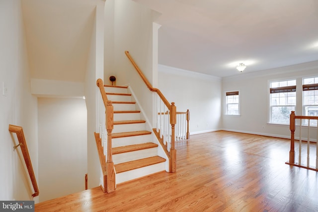 staircase with hardwood / wood-style floors and crown molding