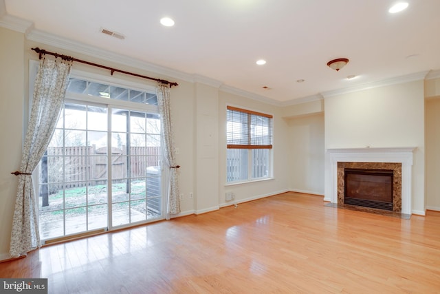 unfurnished living room with crown molding, a fireplace, and light hardwood / wood-style flooring