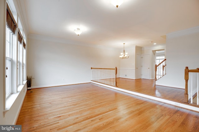 empty room featuring crown molding, light hardwood / wood-style flooring, and a notable chandelier