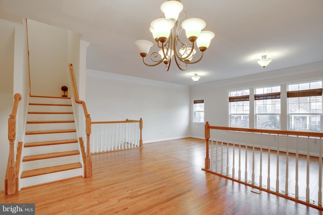 unfurnished room with an inviting chandelier, crown molding, and light hardwood / wood-style floors