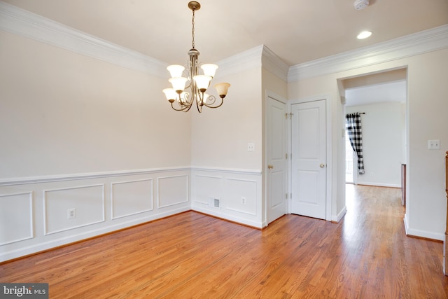 unfurnished room with crown molding, a chandelier, and hardwood / wood-style floors