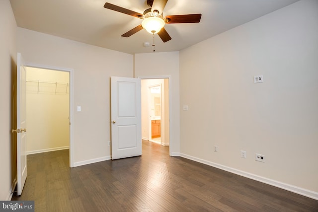 unfurnished bedroom featuring a closet, a walk in closet, dark hardwood / wood-style floors, and ceiling fan