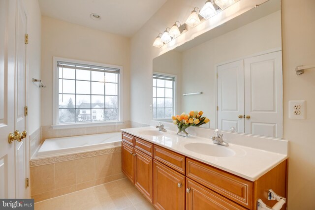 bathroom featuring tiled tub, vanity, and tile patterned flooring