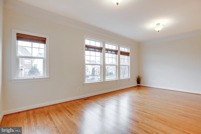 spare room featuring ornamental molding, a healthy amount of sunlight, and light wood-type flooring