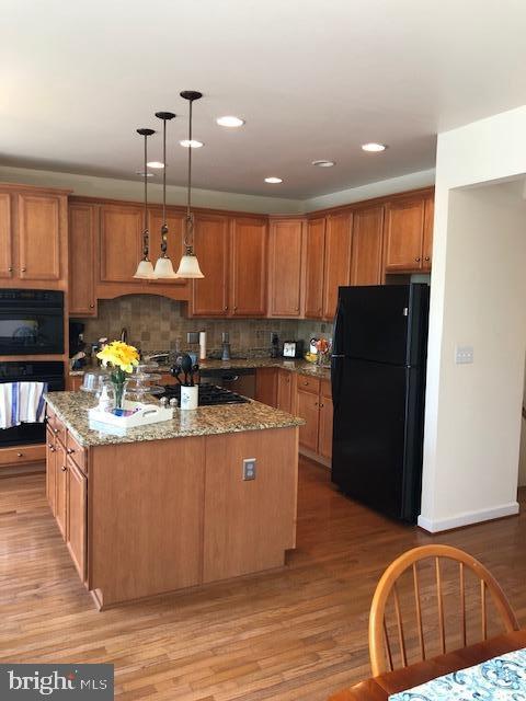 kitchen featuring hanging light fixtures, a kitchen island, light hardwood / wood-style flooring, and black appliances