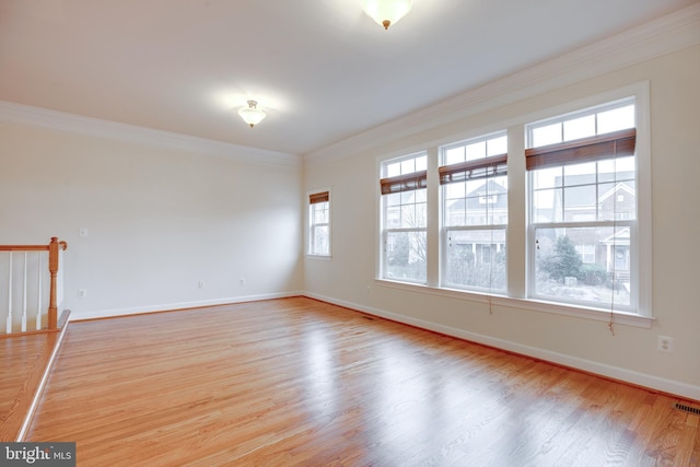 empty room with crown molding and light hardwood / wood-style floors